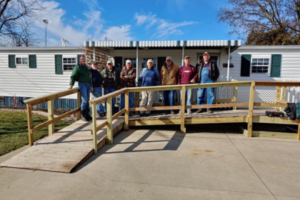 A group of St. John Builders volunteers with a wheelchair ramp they built.